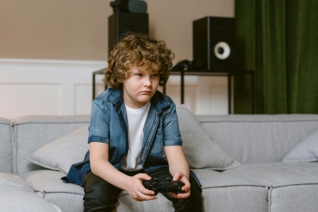 Niño sentado en el sofa jugando videojuegos
